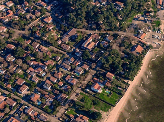 Vue aérienne d'un quartier côtier à Arcachon, illustrant la forte densité des rues près des plages où le stationnement est difficile